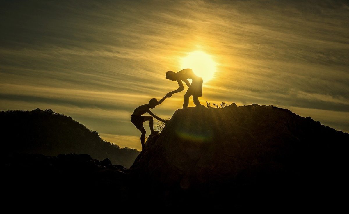 山の頂上で人を助け引き上げる人