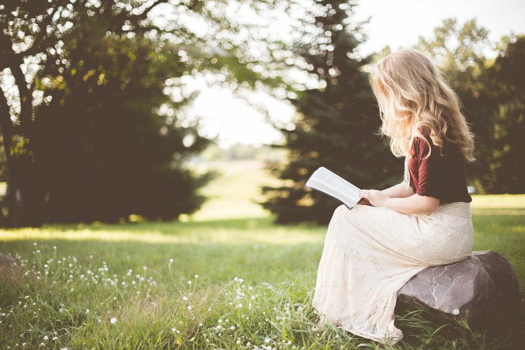 自然の芝生の上で読書をする少女
